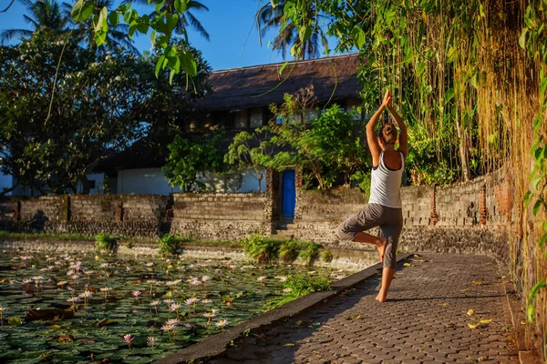 Donna pratica yoga su un lago con ninfee di loto — Foto Stock