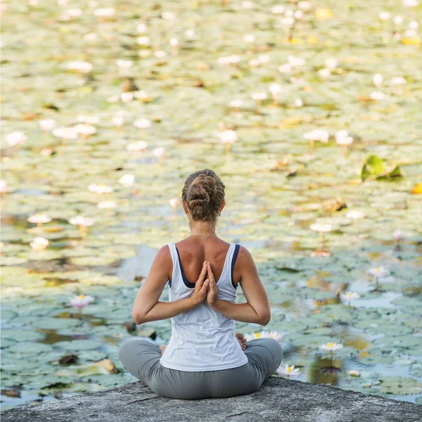 Kvinna praxis yoga på en sjö med Lotus näckrosor — Stockfoto