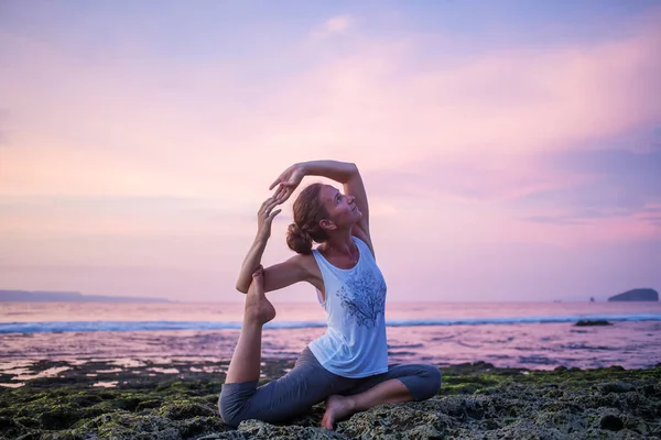 Kaukasisk kvinna utövar yoga på stranden — Stockfoto