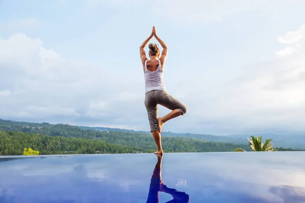 Femme blanche pratiquant le yoga au bord de la piscine — Photo