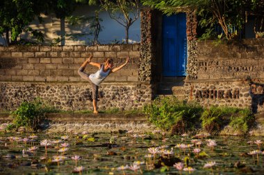 Kadın lotus nilüferler ile bir göl üzerinde yoga uygulamaları