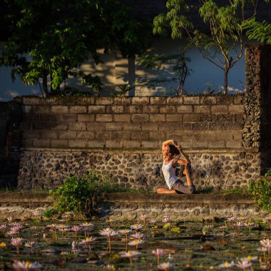 Kadın lotus nilüferler ile bir göl üzerinde yoga uygulamaları