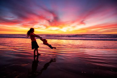 anne ve oğlu sahilde gün batımında eğleniyor