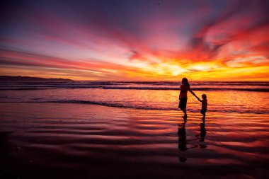 anne ve oğlu sahilde gün batımında eğleniyor