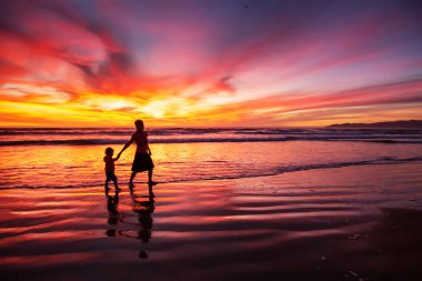 anne ve oğlu sahilde gün batımında eğleniyor