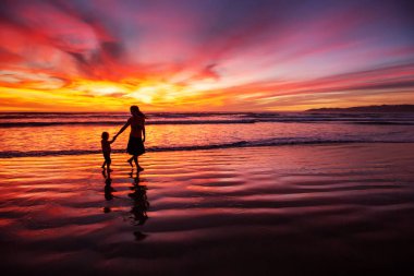 anne ve oğlu sahilde gün batımında eğleniyor