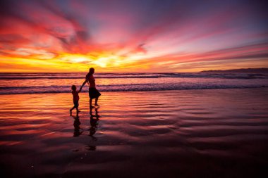 anne ve oğlu sahilde gün batımında eğleniyor