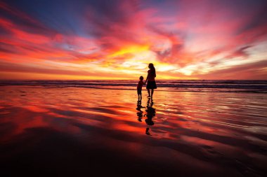 anne ve oğlu sahilde gün batımında eğleniyor