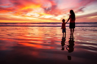 anne ve oğlu sahilde gün batımında eğleniyor
