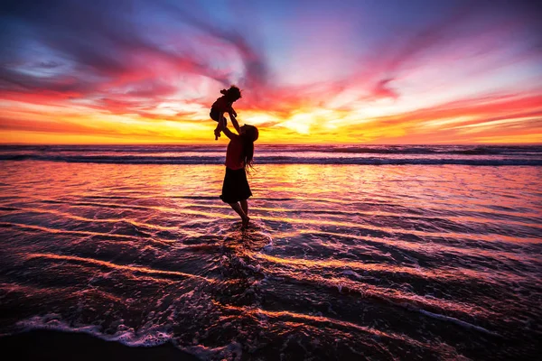Madre e figlio si divertono al tramonto sulla spiaggia — Foto Stock