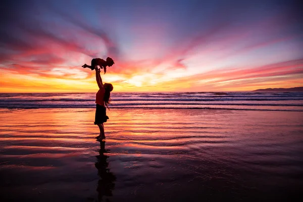 Madre e figlio si divertono al tramonto sulla spiaggia — Foto Stock