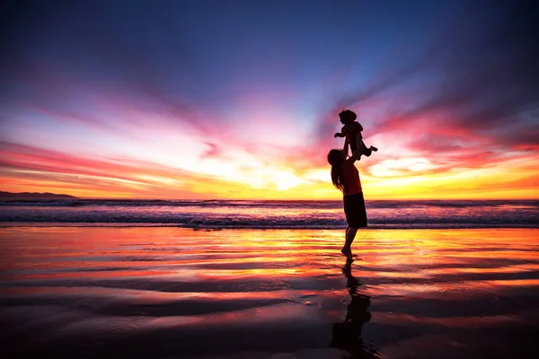 Madre e hijo divirtiéndose al atardecer en la playa — Foto de Stock