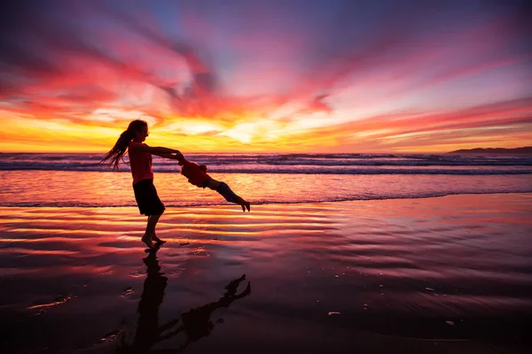 Madre e hijo divirtiéndose al atardecer en la playa — Foto de Stock