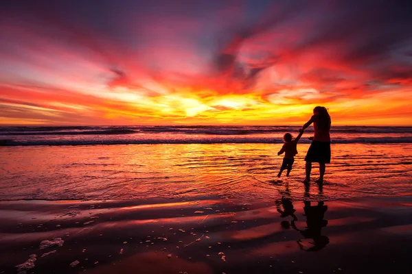 Madre e figlio si divertono al tramonto sulla spiaggia — Foto Stock