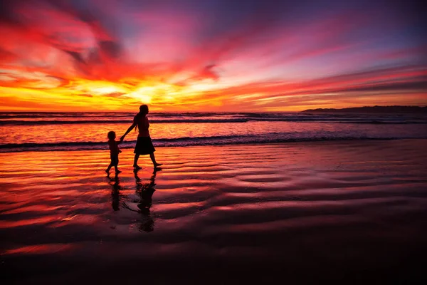 Madre e figlio si divertono al tramonto sulla spiaggia — Foto Stock