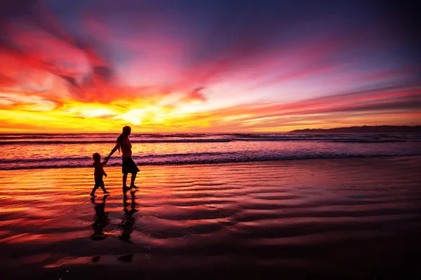 Matka i syn bawią się o zachodzie słońca na plaży — Zdjęcie stockowe