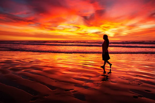 Mulher andando sozinha na praia ao pôr do sol — Fotografia de Stock