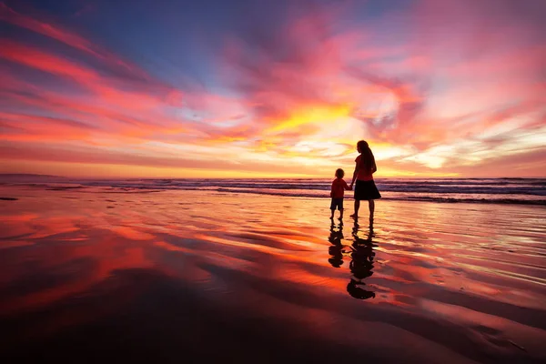 Madre e figlio si divertono al tramonto sulla spiaggia — Foto Stock