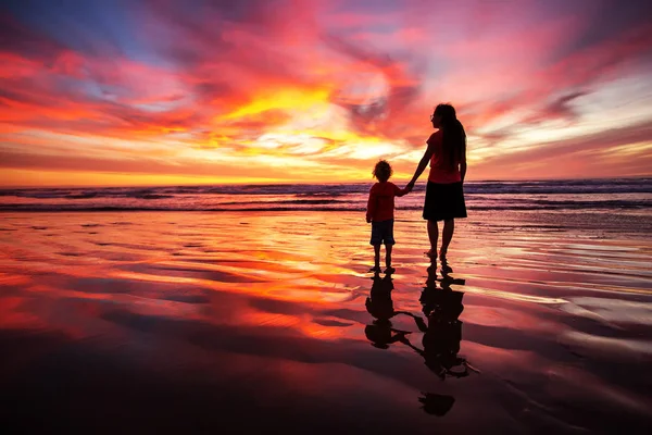 Madre e figlio si divertono al tramonto sulla spiaggia — Foto Stock