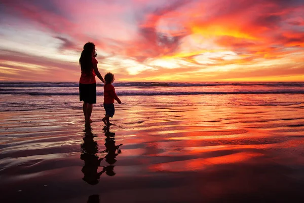 Madre e hijo divirtiéndose al atardecer en la playa — Foto de Stock