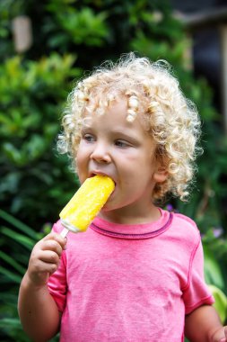  sarışın kıvırcık saçlı küçük çocuk dondurma yiyor 