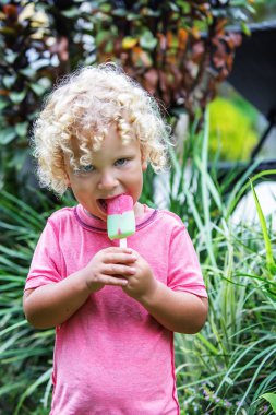  sarışın kıvırcık saçlı küçük çocuk dondurma yiyor 