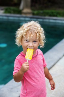  sarışın kıvırcık saçlı küçük çocuk dondurma yiyor 