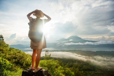 Batur, Bali, Indon dağının tepesinden gün doğumunun tadını çıkaran kadın