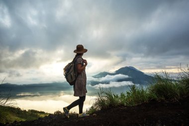 Batur, Bali, Indon dağının tepesinden gün doğumunun tadını çıkaran kadın