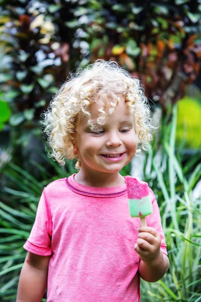 little boy with blonde curly hair is eating ice cream