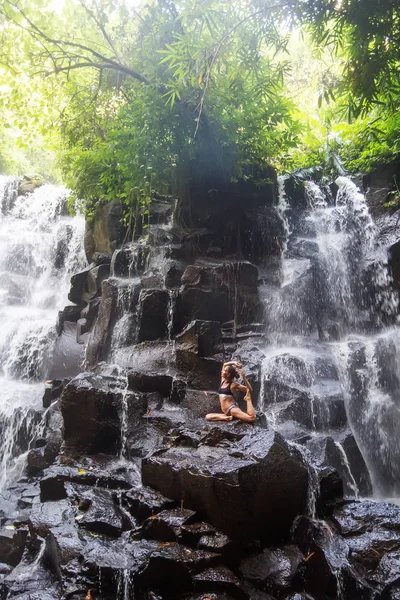 Mujer practica yoga cerca de cascada en Bali, Indonesia —  Fotos de Stock