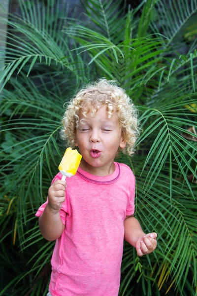 Niño pequeño con el pelo rubio rizado está comiendo helado — Foto de Stock