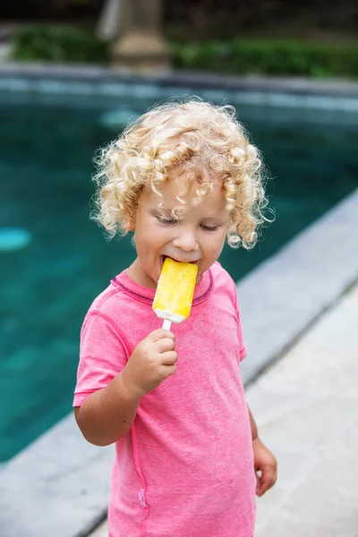 Niño pequeño con el pelo rubio rizado está comiendo helado — Foto de Stock