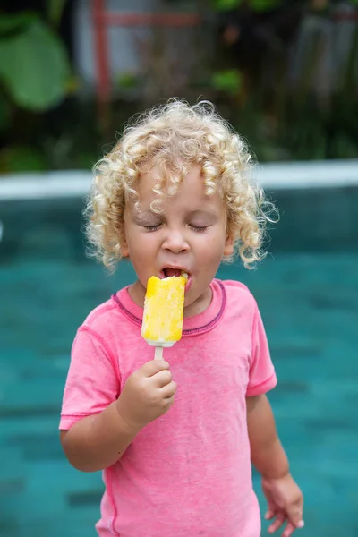 Niño pequeño con el pelo rubio rizado está comiendo helado — Foto de Stock