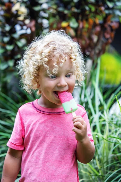 Niño pequeño con el pelo rubio rizado está comiendo helado — Foto de Stock