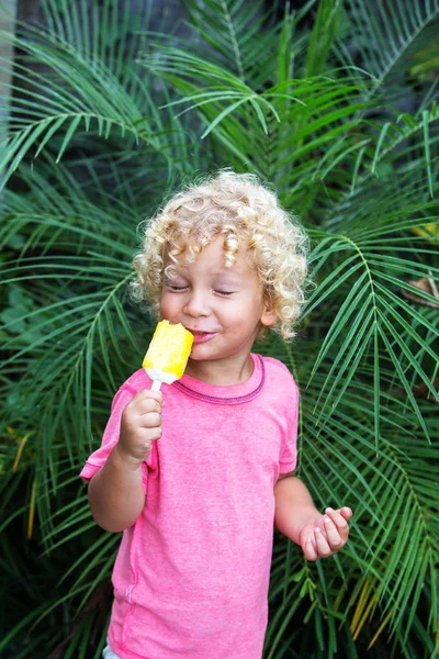 Niño pequeño con el pelo rubio rizado está comiendo helado — Foto de Stock