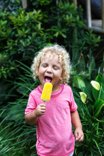 Niño pequeño con el pelo rubio rizado está comiendo helado — Foto de Stock