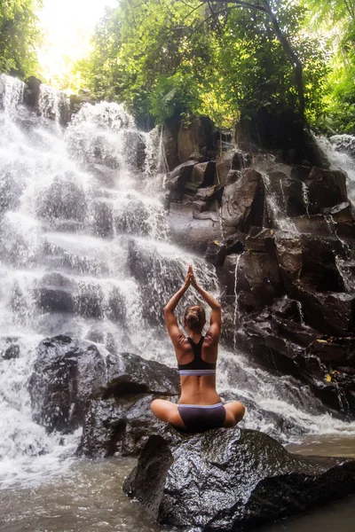 Mulher pratica ioga perto de cachoeira em Bali, Indonésia — Fotografia de Stock