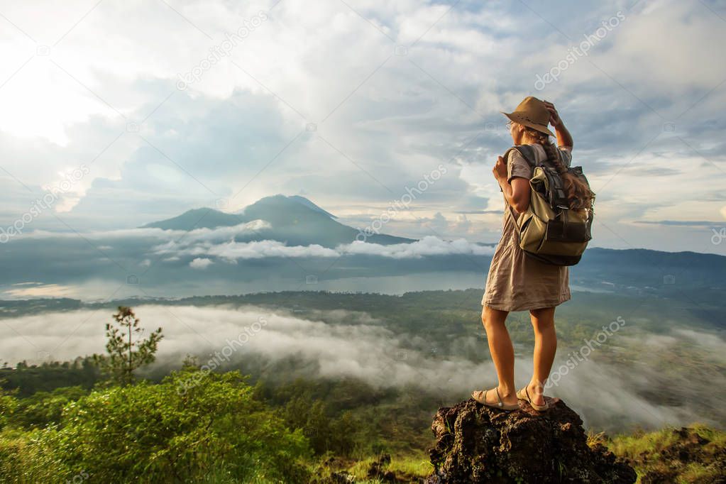 Woman enjoying sunrise from a top of mountain Batur, Bali, Indon