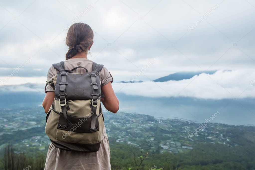 Woman enjoying sunrise from a top of mountain Batur, Bali, Indon