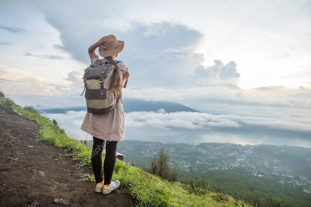 Woman enjoying sunrise from a top of mountain Batur, Bali, Indon