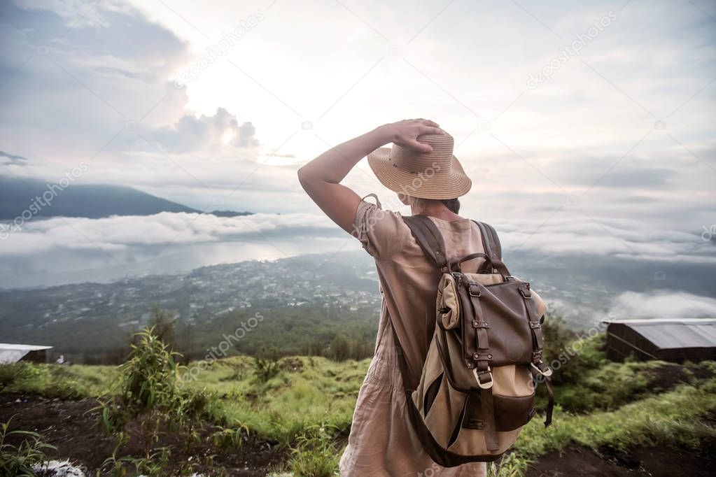 Woman enjoying sunrise from a top of mountain Batur, Bali, Indon