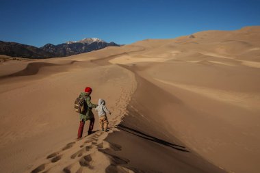 Oğluyla çölde yürüyüş yapan bir adam.