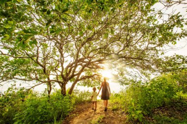 Anne ve oğlu büyük bir ağacın arkasında. 