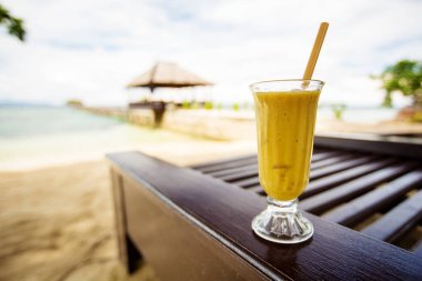Tropikal denizin önünde mango suyu var.