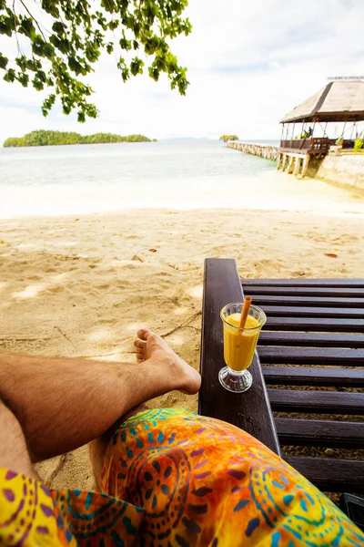 Man drinks mango juice on the beach