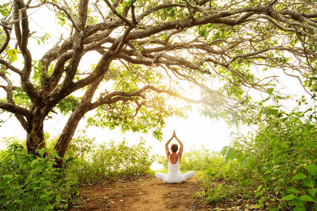 Woman practicing yoga at sunset