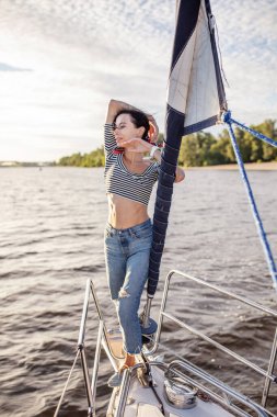 Güzel kız gün batımında bir yatta dinleniyor.