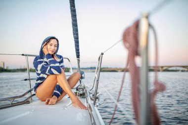 Güzel kız gün batımında bir yatta dinleniyor.