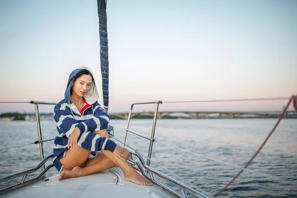 Güzel kız gün batımında bir yatta dinleniyor.